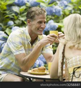 Mature couple having tea in a lawn and smiling