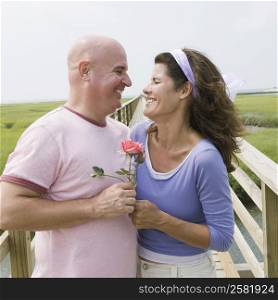 Mature couple holding a rose and smiling