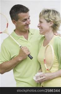 Mature couple holding badminton rackets and looking at each other