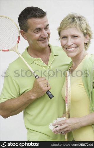 Mature couple holding badminton rackets and smiling