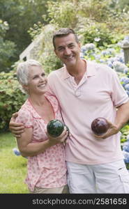 Mature couple holding bocce balls and smiling