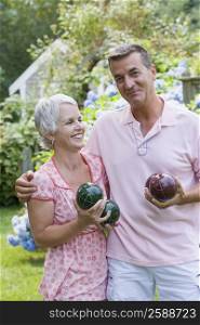 Mature couple holding bocce balls and smiling