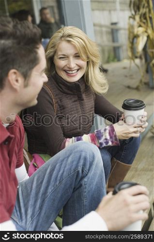 Mature couple holding disposable cups and smiling