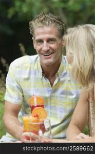 Mature couple holding glasses of juice and smiling