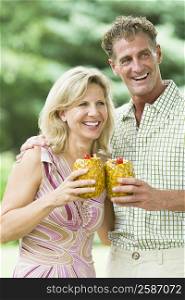 Mature couple holding pineapples and smiling
