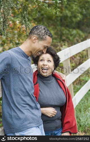 Mature couple leaning against a fence and smiling
