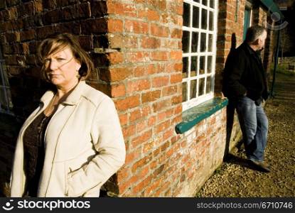 Mature couple leaning against walls of a house