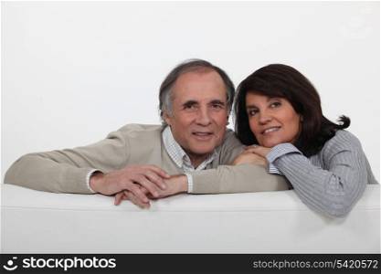 Mature couple leaning on back of sofa