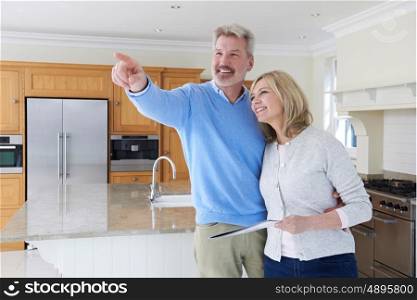 Mature Couple Looking Around Kitchen Of House For Sale