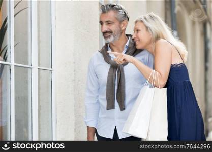 mature couple looking at fashion store window