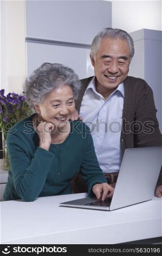 Mature Couple Looking at Laptop in the Kitchen