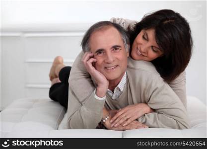 mature couple lying in bed showing their affection