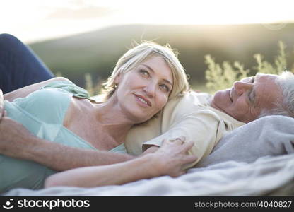 Mature couple lying together on blanket smiling