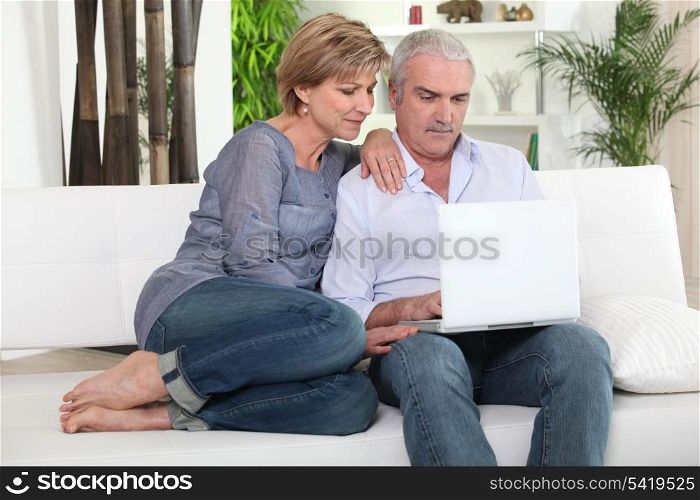 Mature couple on sofa with computer