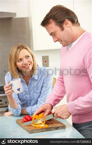 Mature couple preparing meal in domestic kitchen