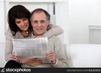 Mature couple reading a newspaper