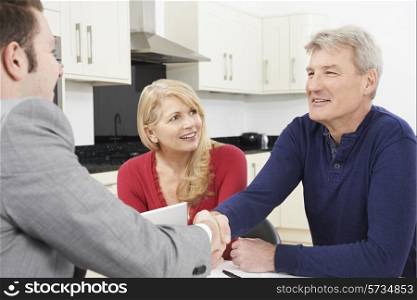 Mature Couple Shaking Hands With Financial Advisor At Home
