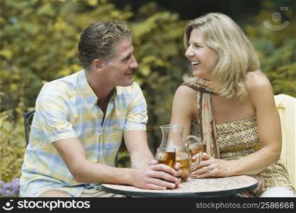 Mature couple sitting at a table and holding glasses of ice tea