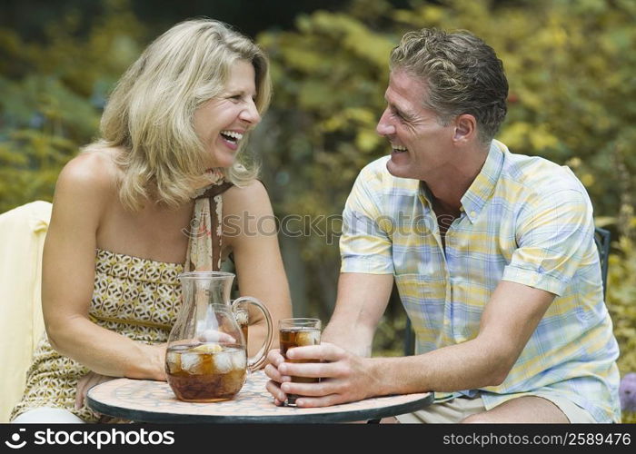 Mature couple sitting at a table in a lawn and laughing