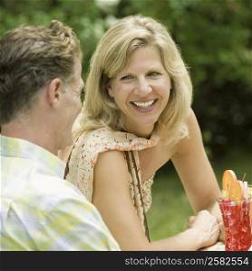 Mature couple sitting at a table in a lawn and smiling