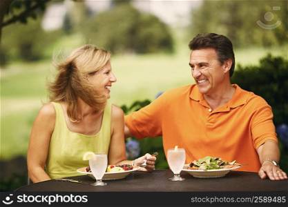 Mature couple sitting at the table with plates of salad in front of them