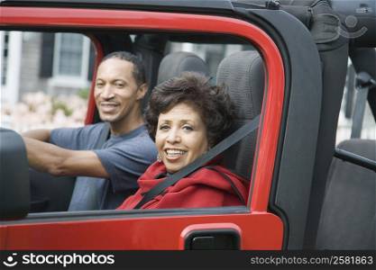 Mature couple sitting in a jeep and smiling