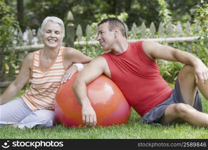 Mature couple sitting in a lawn with a fitness ball