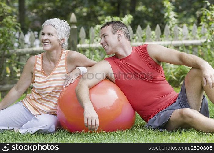Mature couple sitting in a lawn with a fitness ball