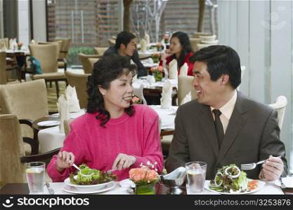 Mature couple sitting in a restaurant looking at each other