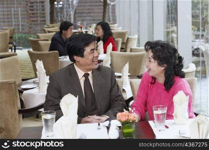 Mature couple sitting in a restaurant looking at each other
