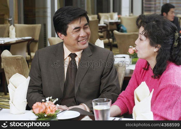 Mature couple sitting in a restaurant looking at each other