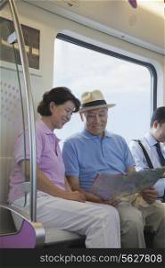 Mature couple sitting in the subway and looking at the map