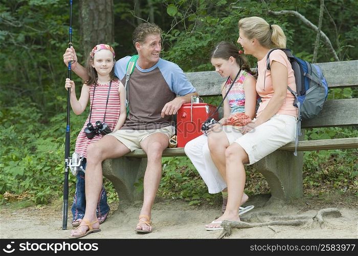 Mature couple sitting on a bench with their children