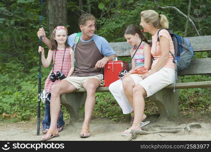 Mature couple sitting on a bench with their children