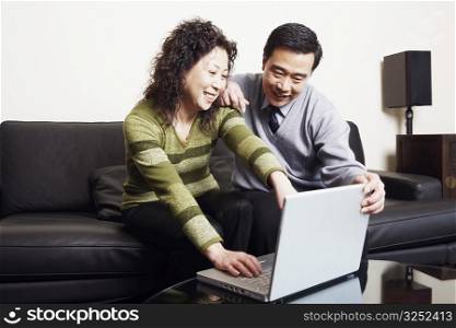 Mature couple sitting on a couch using a laptop