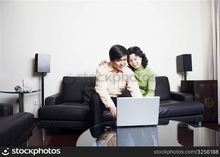 Mature couple sitting on a couch using a laptop