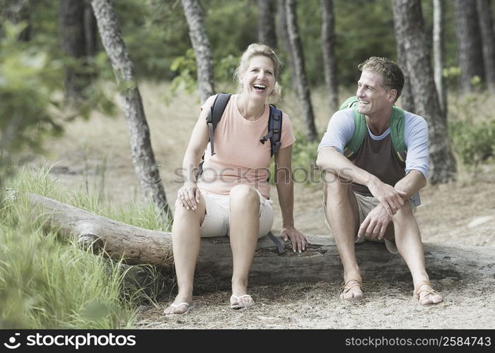 Mature couple sitting on a tree trunk in a forest