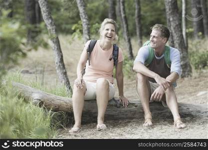 Mature couple sitting on a tree trunk in a forest
