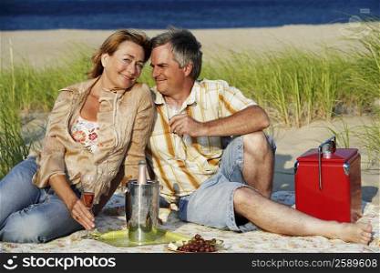 Mature couple sitting on the beach and holding champagne flutes