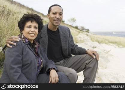 Mature couple sitting on the beach and smiling