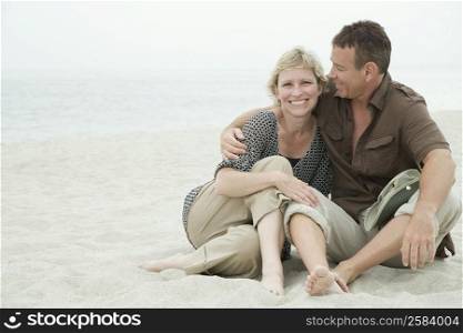 Mature couple sitting on the beach and smiling