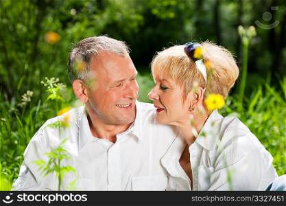 Mature couple sitting out in the green on a beautiful summer day
