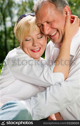 Mature couple sitting out in the green on a beautiful summer day