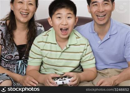 Mature couple sitting with their son playing video game