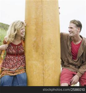 Mature couple smiling with a surfboard