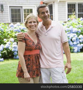 Mature couple standing in a garden with arm around