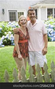 Mature couple standing in a garden with arm around