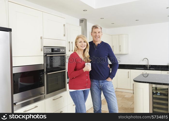 Mature Couple Standing In Beautiful Fitted Kitchen Together