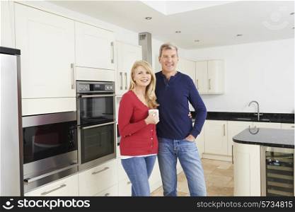 Mature Couple Standing In Beautiful Fitted Kitchen Together