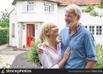 Mature Couple Standing In Garden In Front Of Dream Home In Countryside